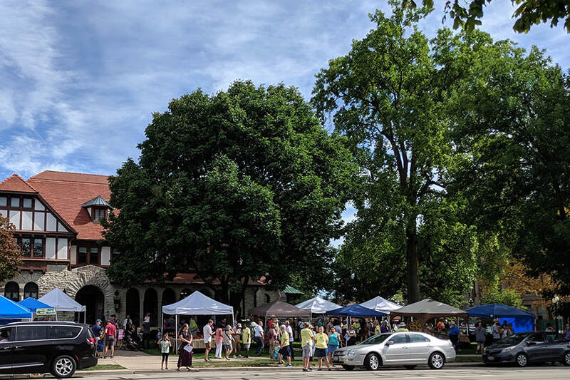 Artisan Tent Village full of visitors with the Troy Hayner Cultural Center in the background